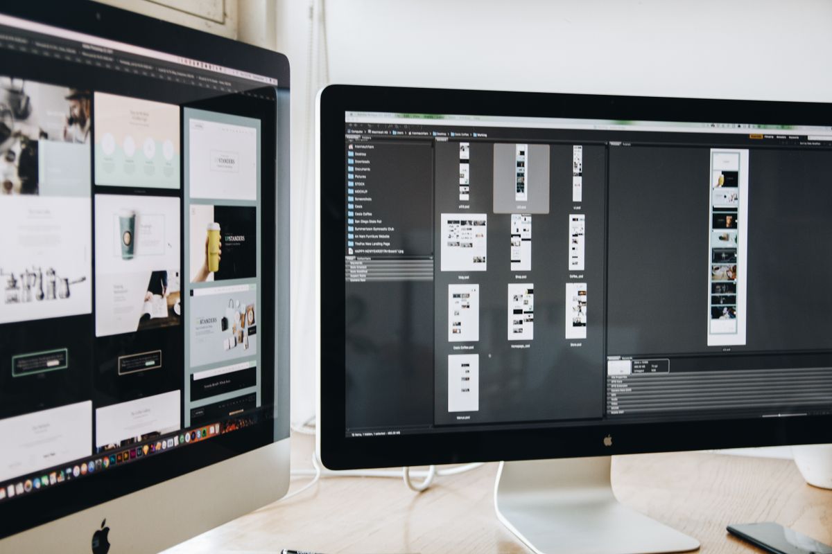 Designer working on website mockups across two monitors